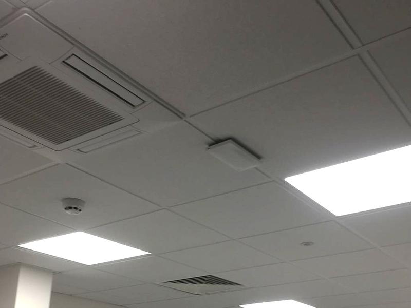 A ceiling-mounted wireless access point above an office meeting room