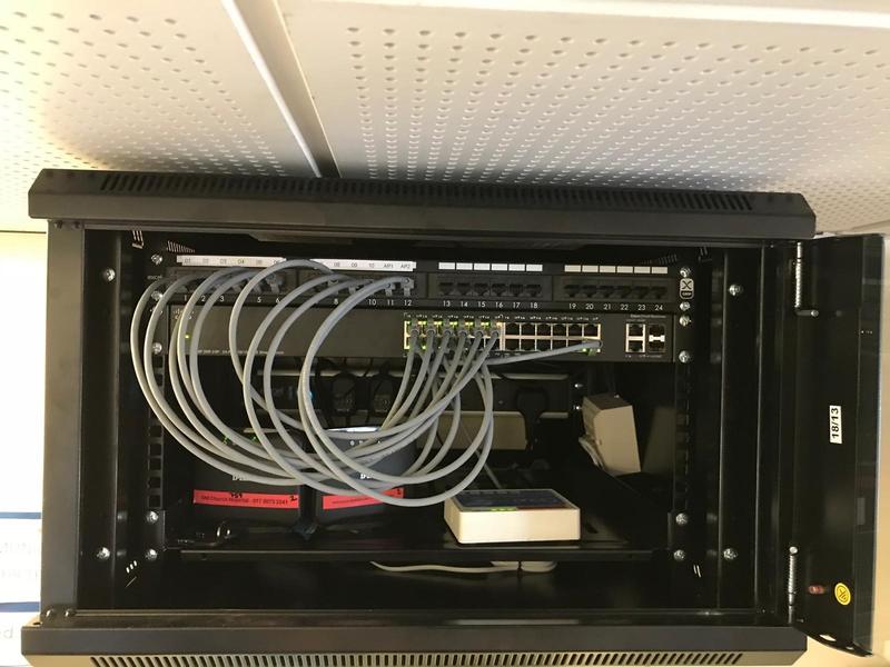 A wall cabinet with ports labelled AP1 and AP2 patched into a PoE switch