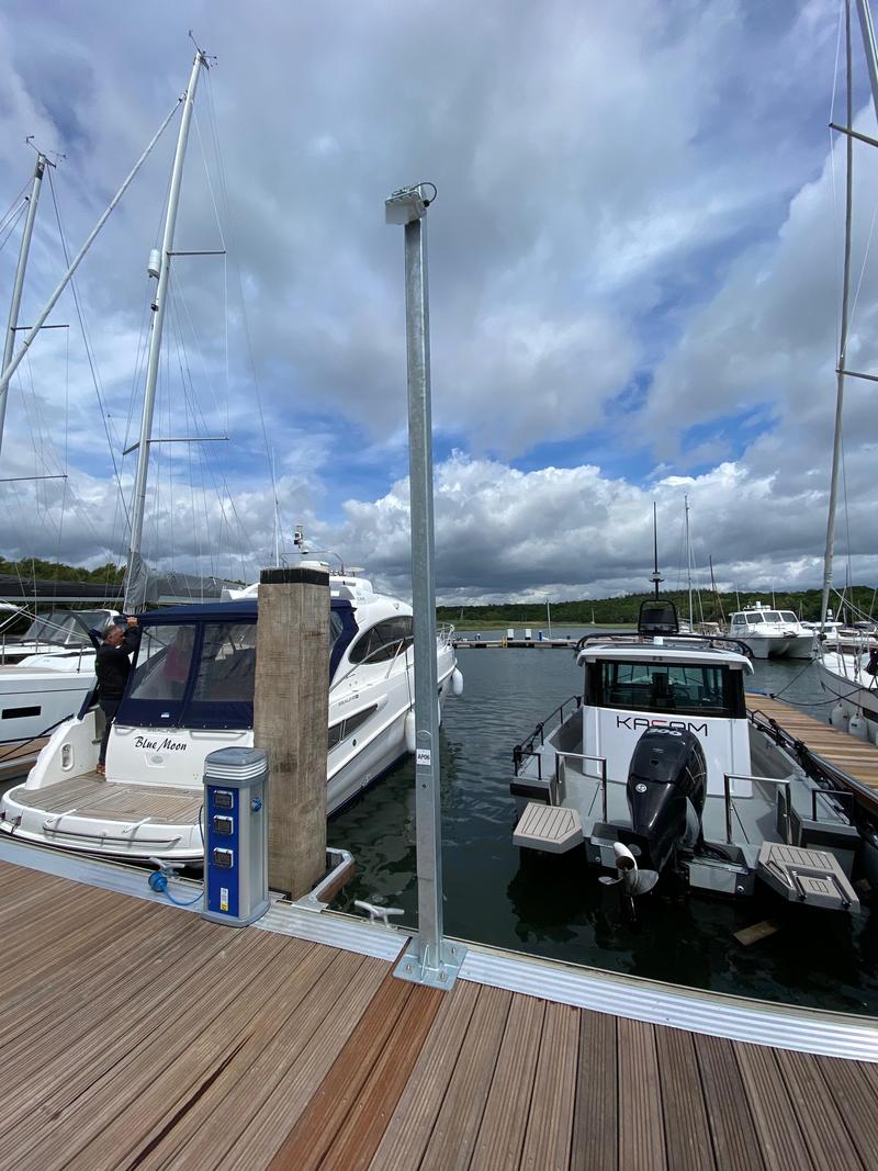 An access point on a post between two occupied berths, with a motor yacht either side and masts behind