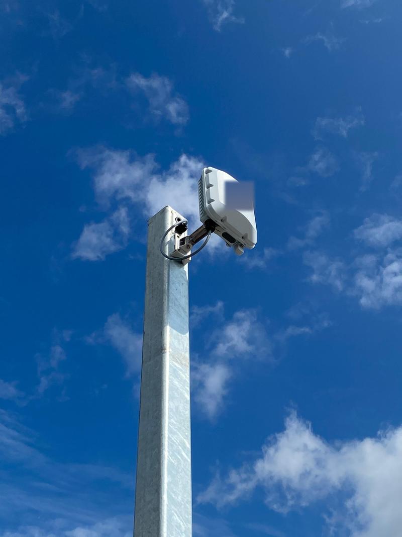 An outdoor access point mounted on a galvanised post against clear blue sky