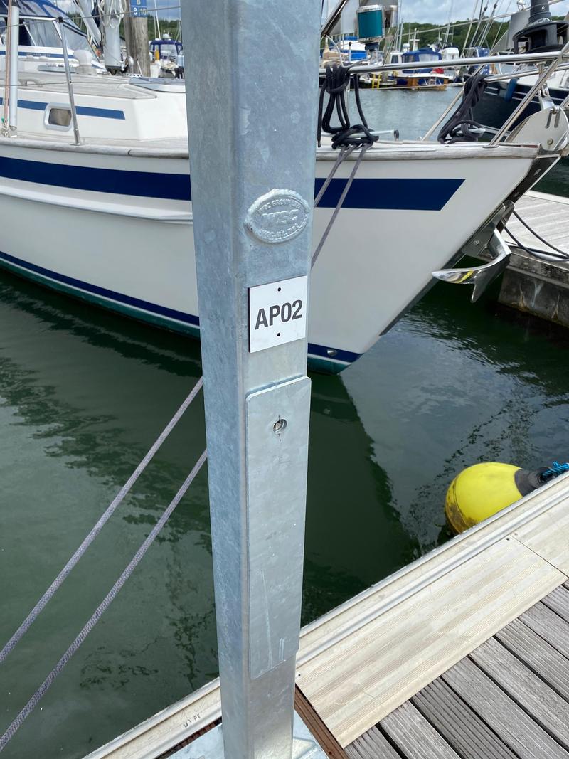 A post-mounted access point carrying an engraved label reading AP02, with vessels moored either side