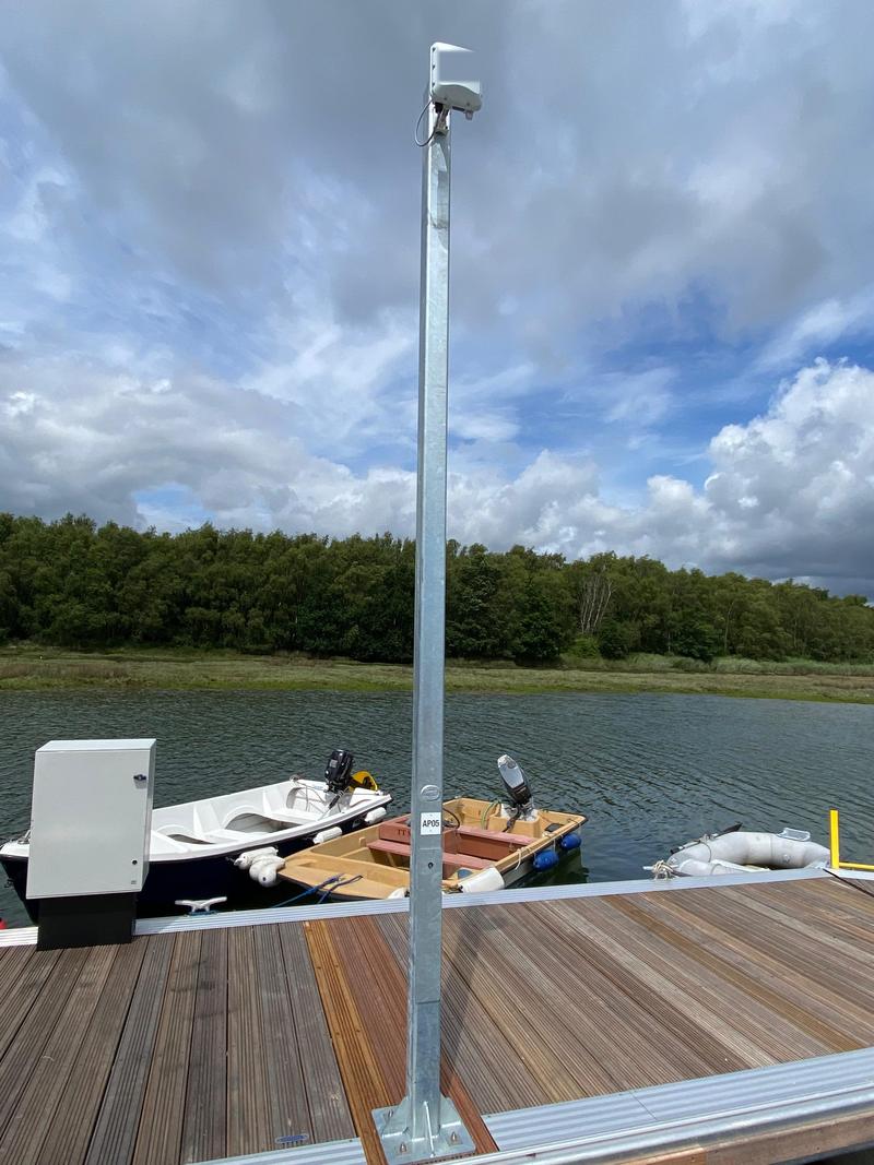 An access point on a post above a pontoon with tenders and a workboat moored alongside
