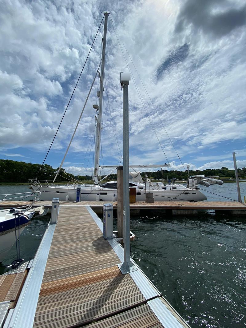 An access point on a post at the head of a pontoon finger with a large sailing yacht moored alongside