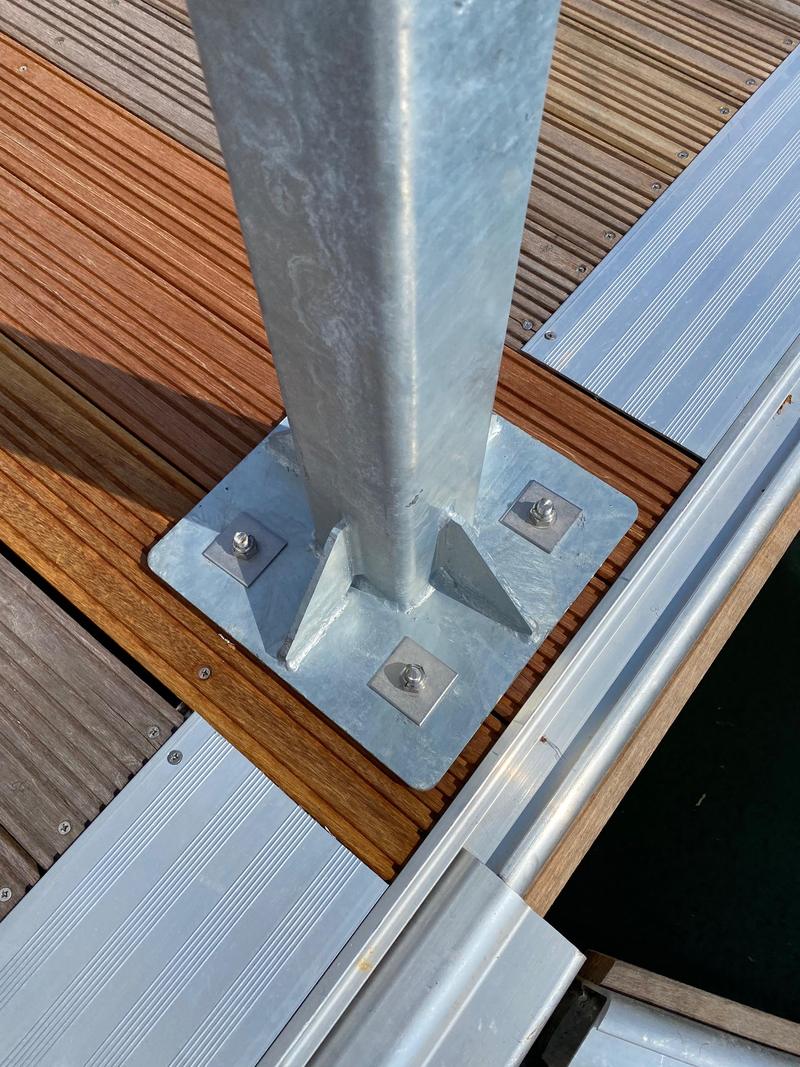 The galvanised base plate of an access point post bolted through a timber pontoon deck